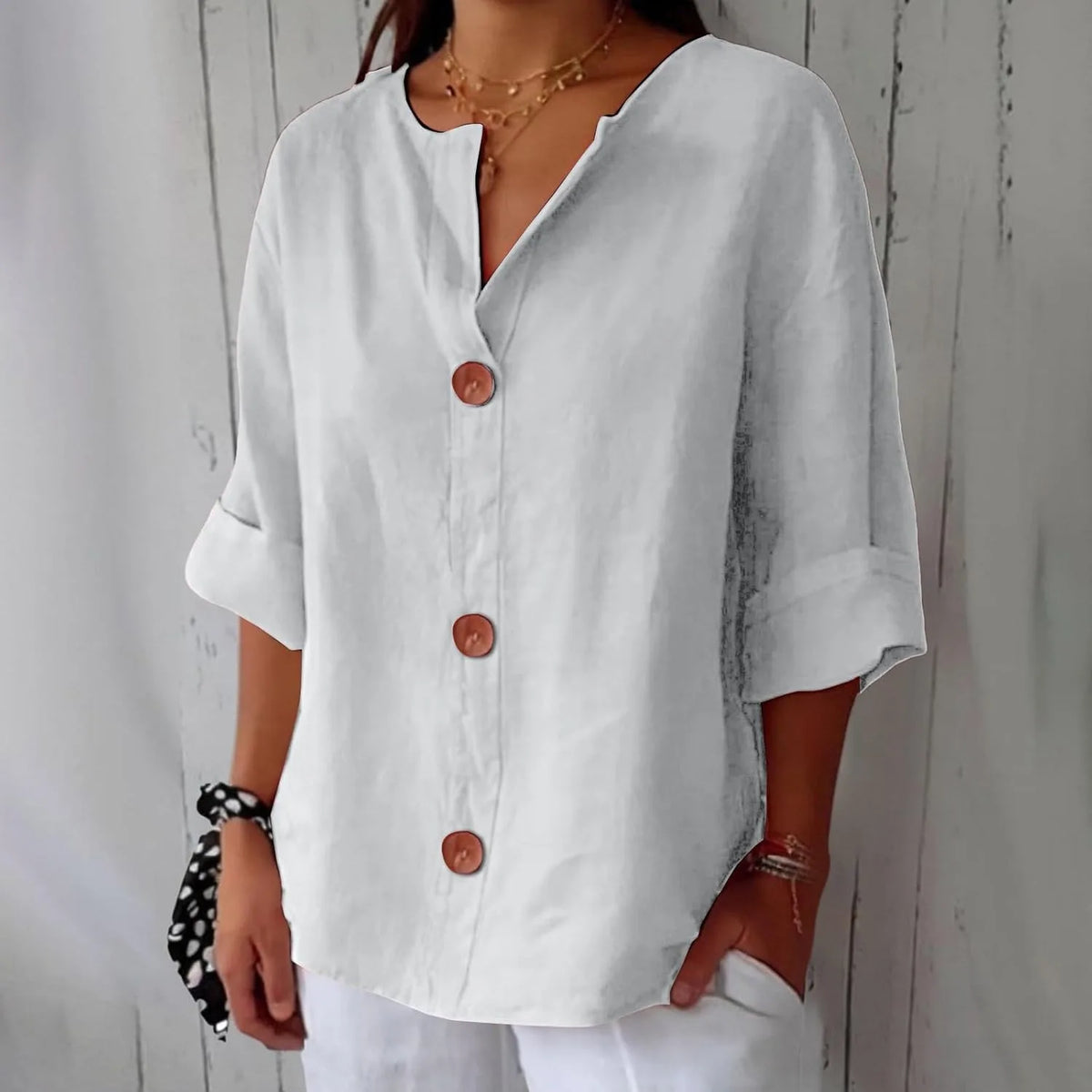 White lightweight blouse with notch collar and wooden button placket, paired with white trousers