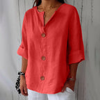 Coral red button-up blouse with cuffed three-quarter sleeves, worn with a black and white polka dot scrunchie