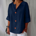 Navy blue relaxed blouse with wooden buttons and V-neckline, shown against a rustic wooden wall