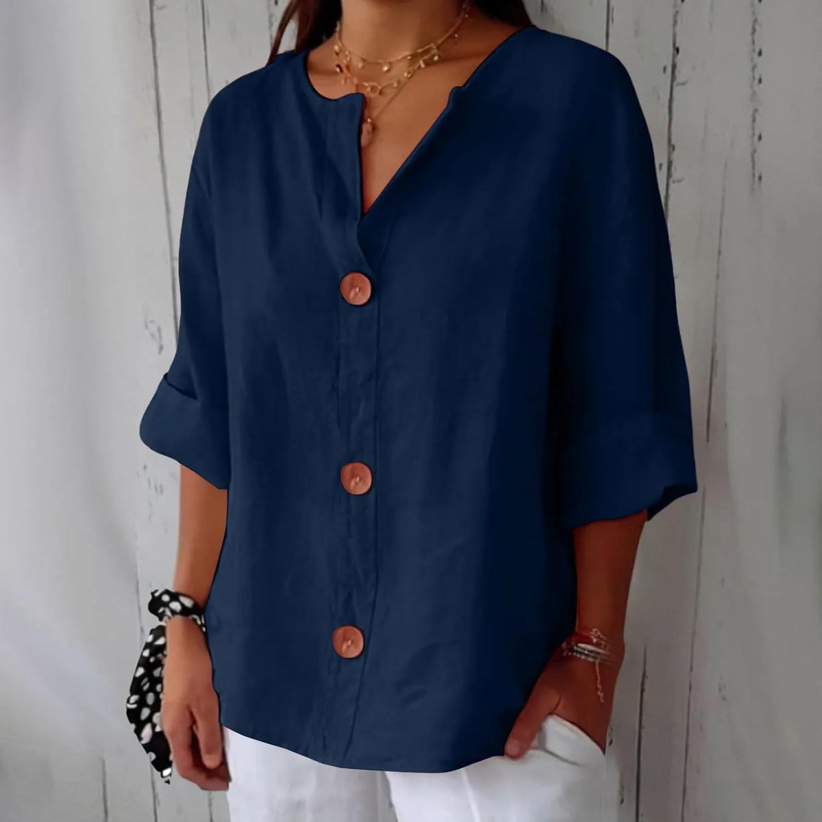 Navy blue relaxed blouse with wooden buttons and V-neckline, shown against a rustic wooden wall