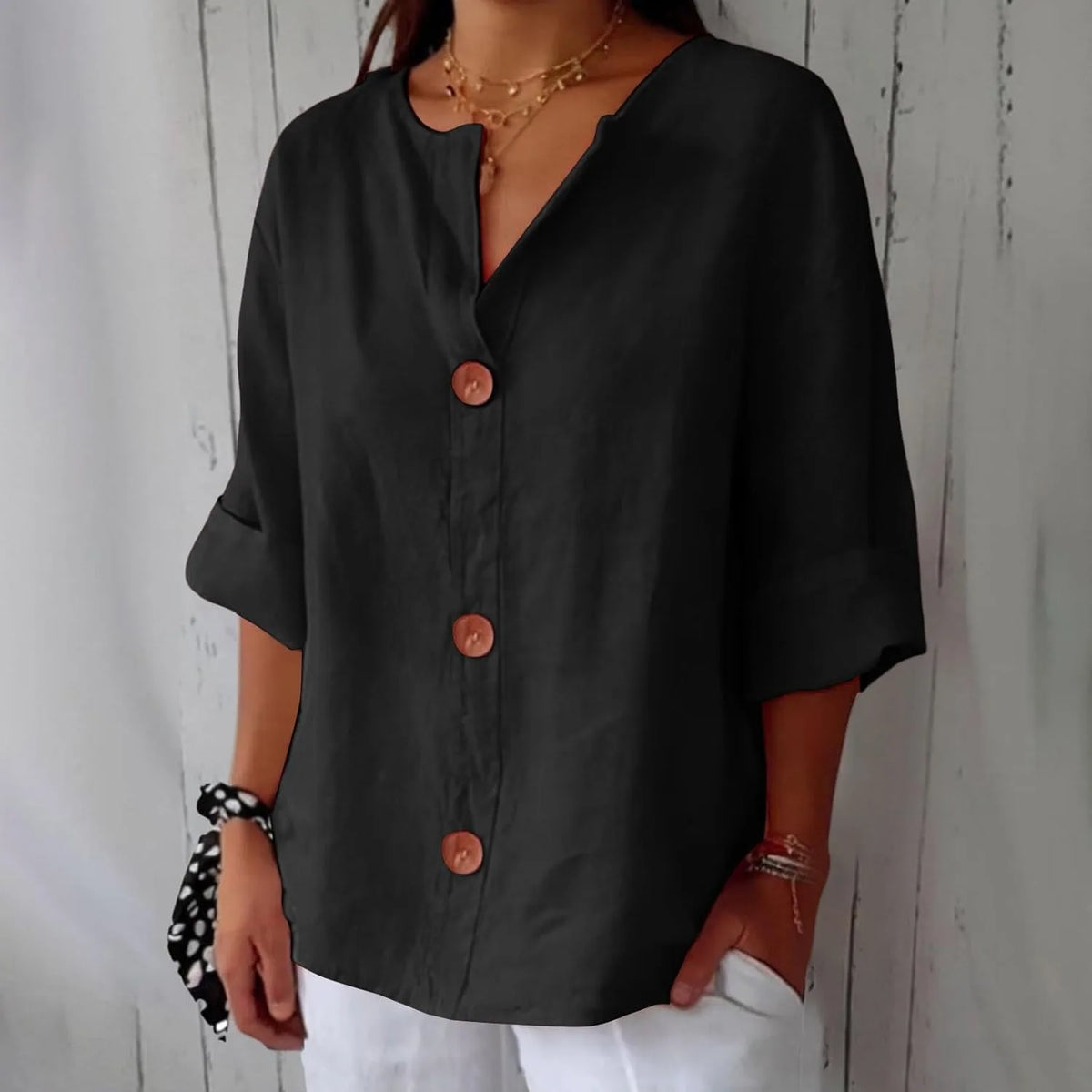 Front close-up of the orange blouse highlighting the wooden button detail and soft fabric drape