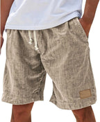 Side angle of khaki cotton shorts showing relaxed fit, pocket and drawstring waistband