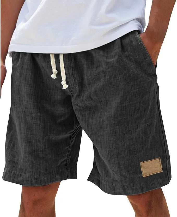 Front angle of khaki cotton shorts showing elastic waistband, side pockets and leather-look patch