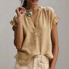 Beige linen-style blouse showing textured fabric, relaxed fit and gathered ruffle detail at the shoulder