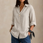 Beige linen blouse with V-neckline and single button, shown with rolled-up sleeves and a gold pendant necklace