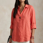 Coral linen blouse with tortoiseshell-style button, collar open and sleeves cuffed above the wrist