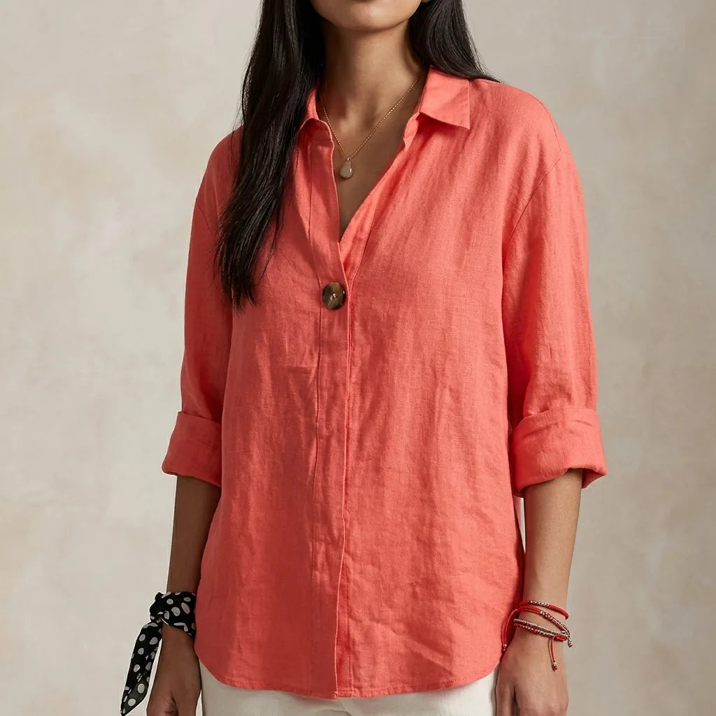Coral linen blouse with tortoiseshell-style button, collar open and sleeves cuffed above the wrist