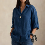 Navy blue linen blouse with open V-neck collar and rolled sleeves, paired with straight leg jeans