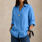 Light blue linen blouse with single button and soft collar, shown with a polka dot tie detail at the cuff