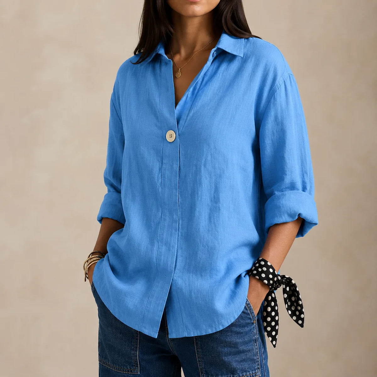 Light blue linen blouse with single button and soft collar, shown with a polka dot tie detail at the cuff