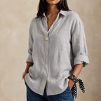 Grey linen blouse with relaxed V-neckline and rolled sleeves, close-up front view showing fabric texture