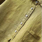 Detail shot of the chest pocket and horizontal seam panel on the olive linen blouse