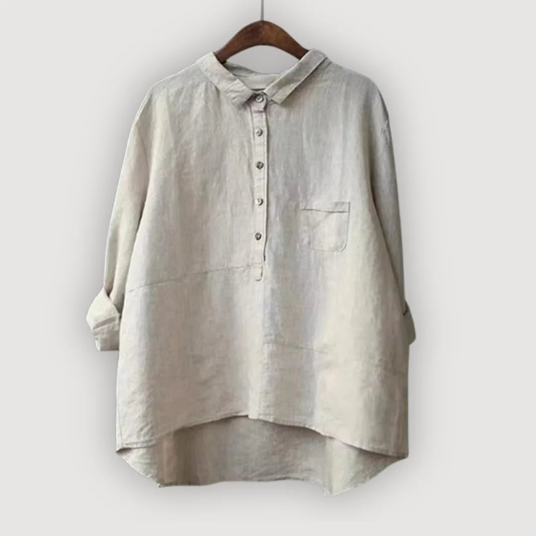 Light oatmeal linen blouse with half-button front and chest pocket, hanging on a dark wooden hanger