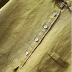 Close-up of the button placket and chest pocket stitching on an olive green linen blouse