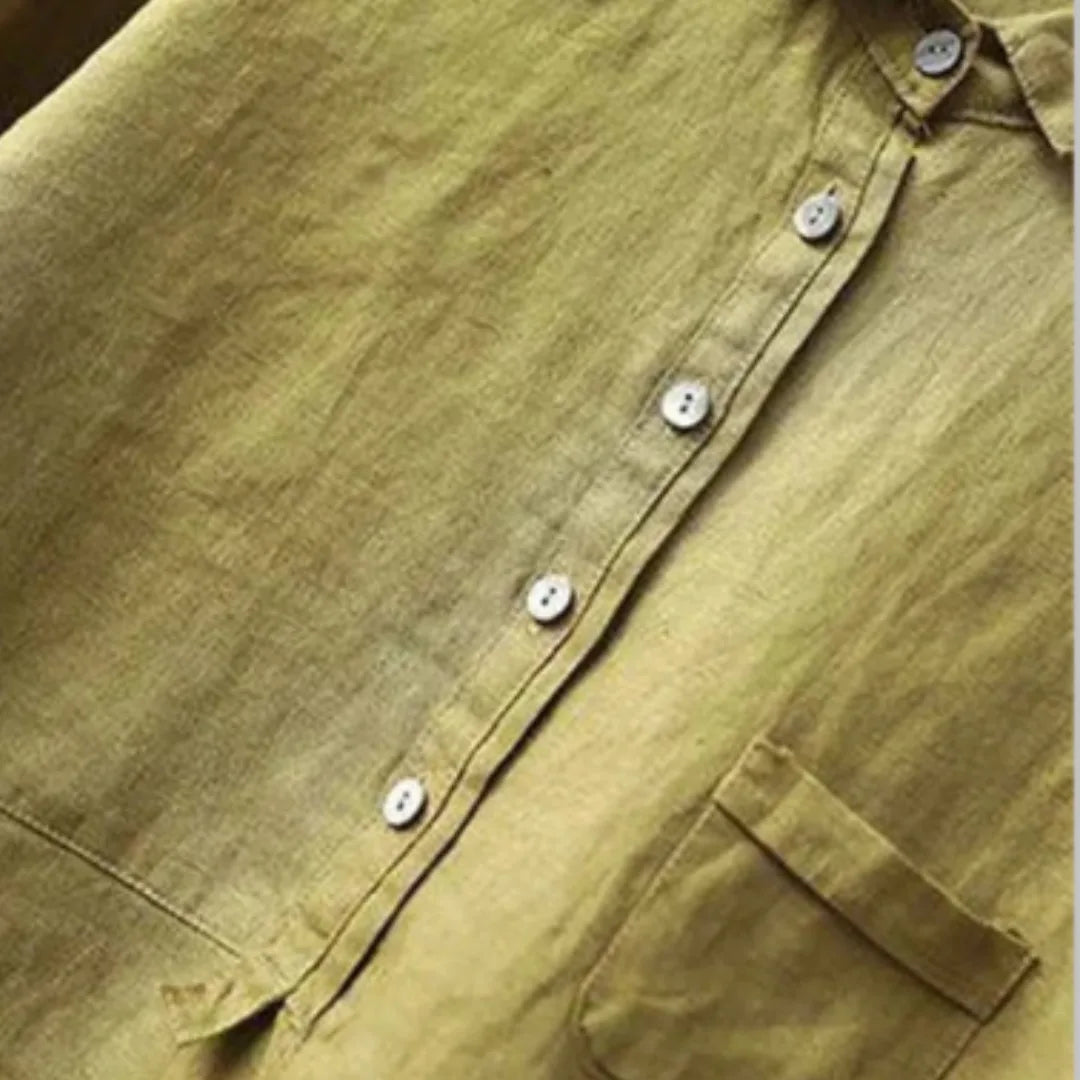 Close-up of the button placket and chest pocket stitching on an olive green linen blouse