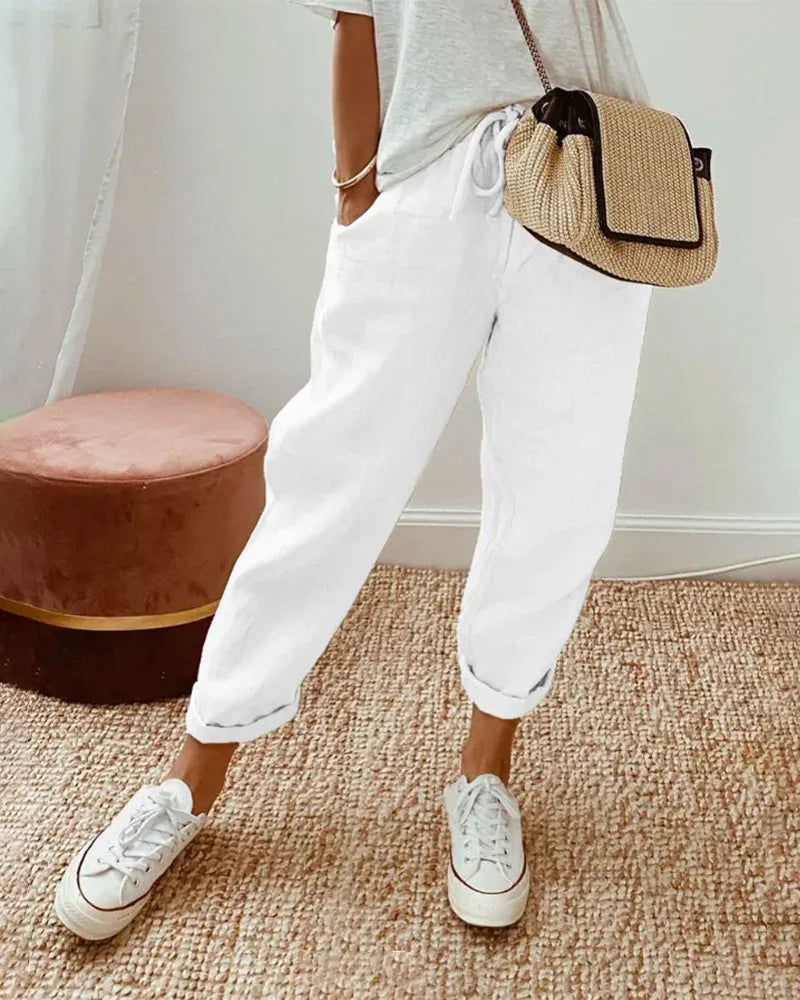 White linen relaxed pants with drawstring tie waist and rolled cuffed hems, front view