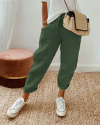 Olive green linen relaxed pants with drawstring waist, cuffed hems and white sneakers