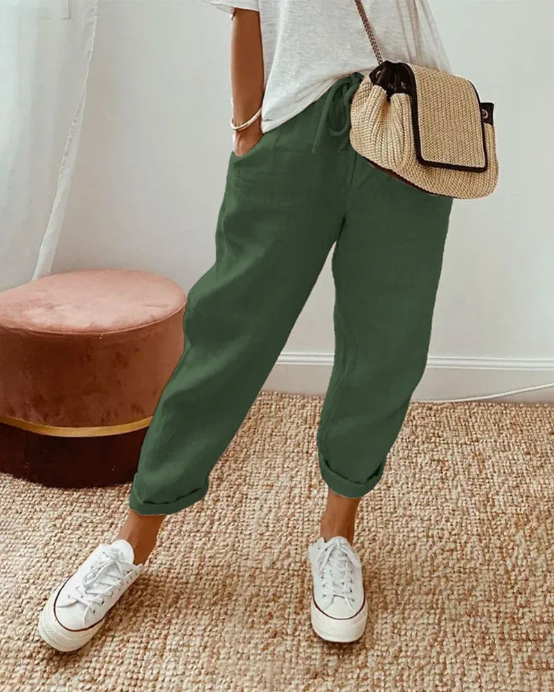 Olive green linen relaxed pants with drawstring waist, cuffed hems and white sneakers