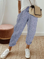 Blue and white striped relaxed pants with drawstring waist, cuffed hems and white sneakers