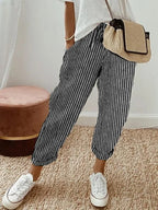 Model wearing beige linen relaxed pants paired with a woven straw crossbody bag