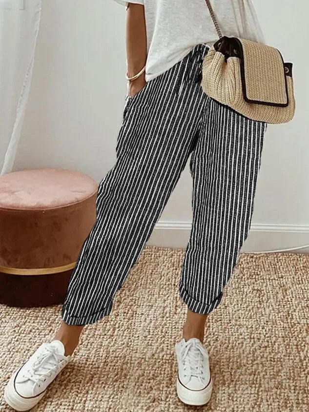 Model wearing beige linen relaxed pants paired with a woven straw crossbody bag