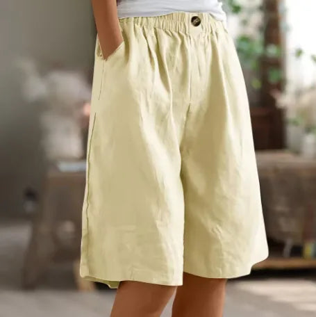 Pale yellow linen-style shorts with elasticated waist and hand resting in the deep side pocket