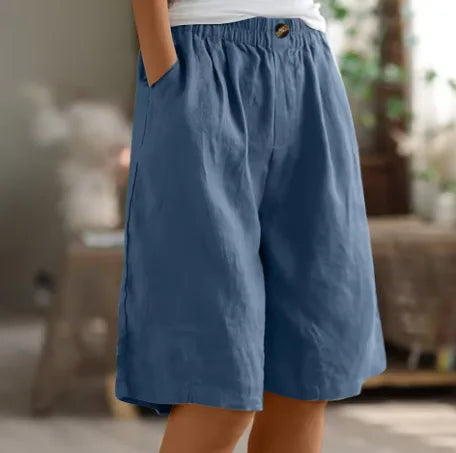 Dusty blue wide-leg shorts shown from the side, highlighting the soft pleated fabric and button waist