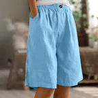 Sky blue wide-leg shorts with elastic waist, button detail and hand tucked into the side pocket