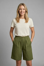 Woman wearing cream t-shirt with relaxed army green linen shorts, elasticated waist and side pockets, front view