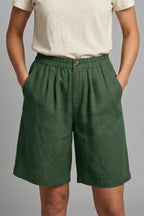Close-up front view of green linen shorts with tortoiseshell button and deep side pocket detail