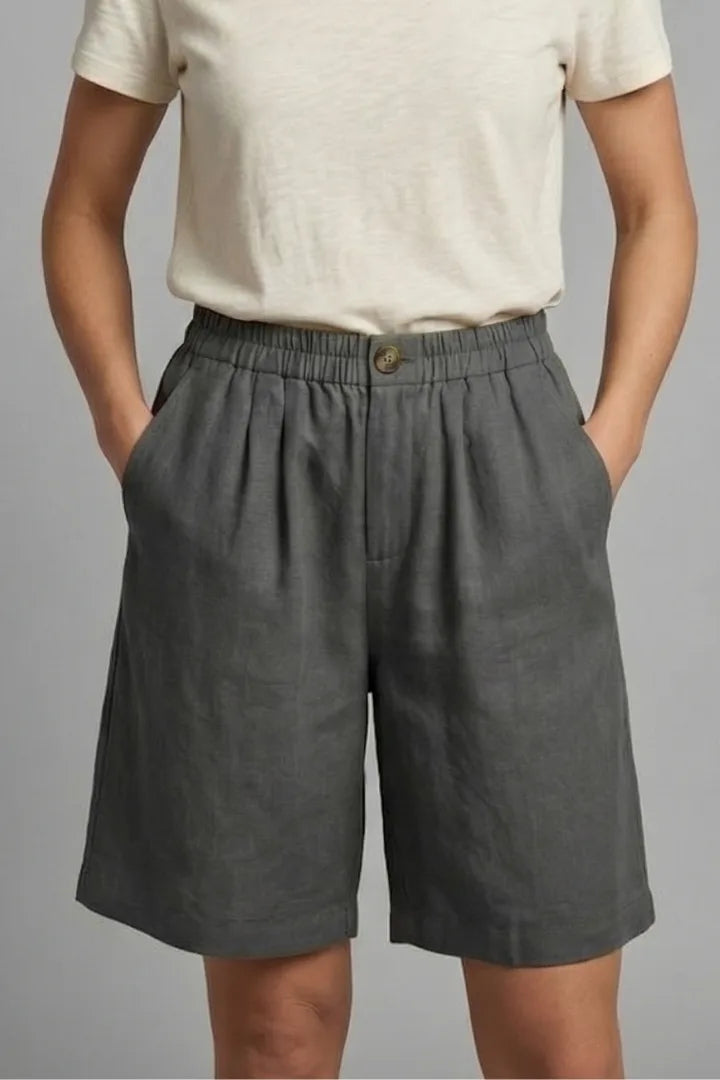 Close-up front view of grey linen shorts showing elasticated waist and relaxed wide leg