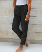 Black linen-style trousers with drawstring waist and straight relaxed leg, paired with bare feet