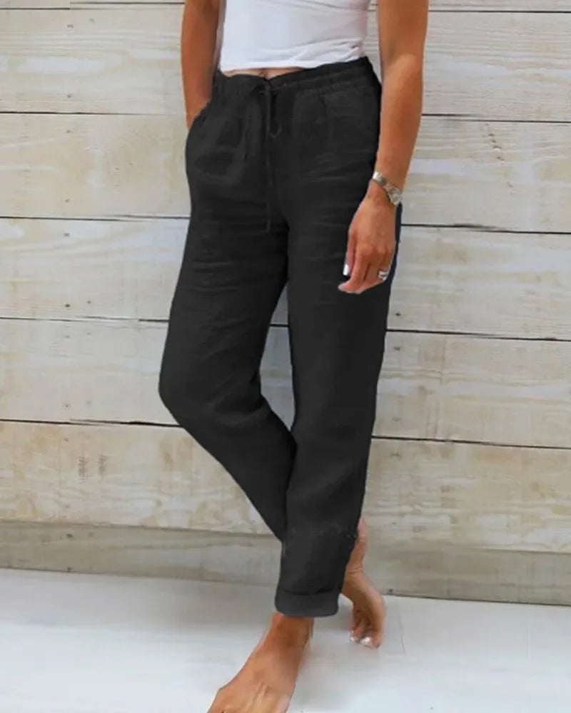 Black linen-style trousers with drawstring waist and straight relaxed leg, paired with bare feet