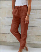 Rust brown linen pants shown from a side angle with drawstring waist and rolled cuff hem