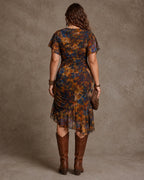 Back view of the rust red floral midi dress showing the fitted waist, flowy skirt and knee-high leather boots