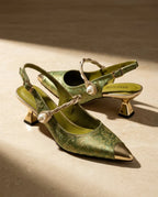 Side view of green floral brocade slingback kitten heels with gold pointed toe cap, twisted pearl vamp strap and sculpted gold heel.