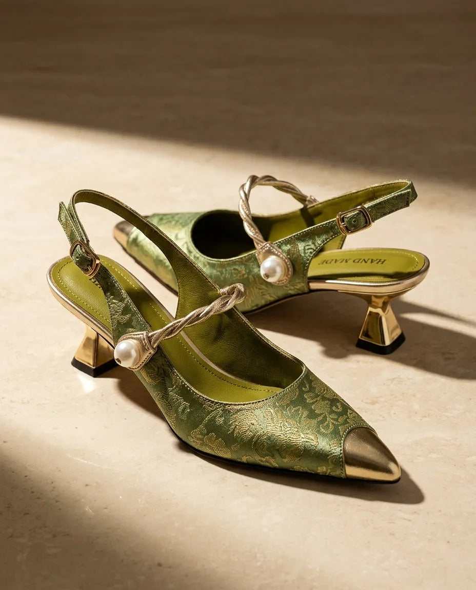 Side view of green floral brocade slingback kitten heels with gold pointed toe cap, twisted pearl vamp strap and sculpted gold heel.