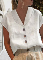 Close-up front view of a white shawl V-neck top with button placket and cap sleeves, soft textured linen-look fabric