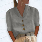 Grey shawl V-neck top with cap sleeves and button placket, shown against a white textured wall backdrop
