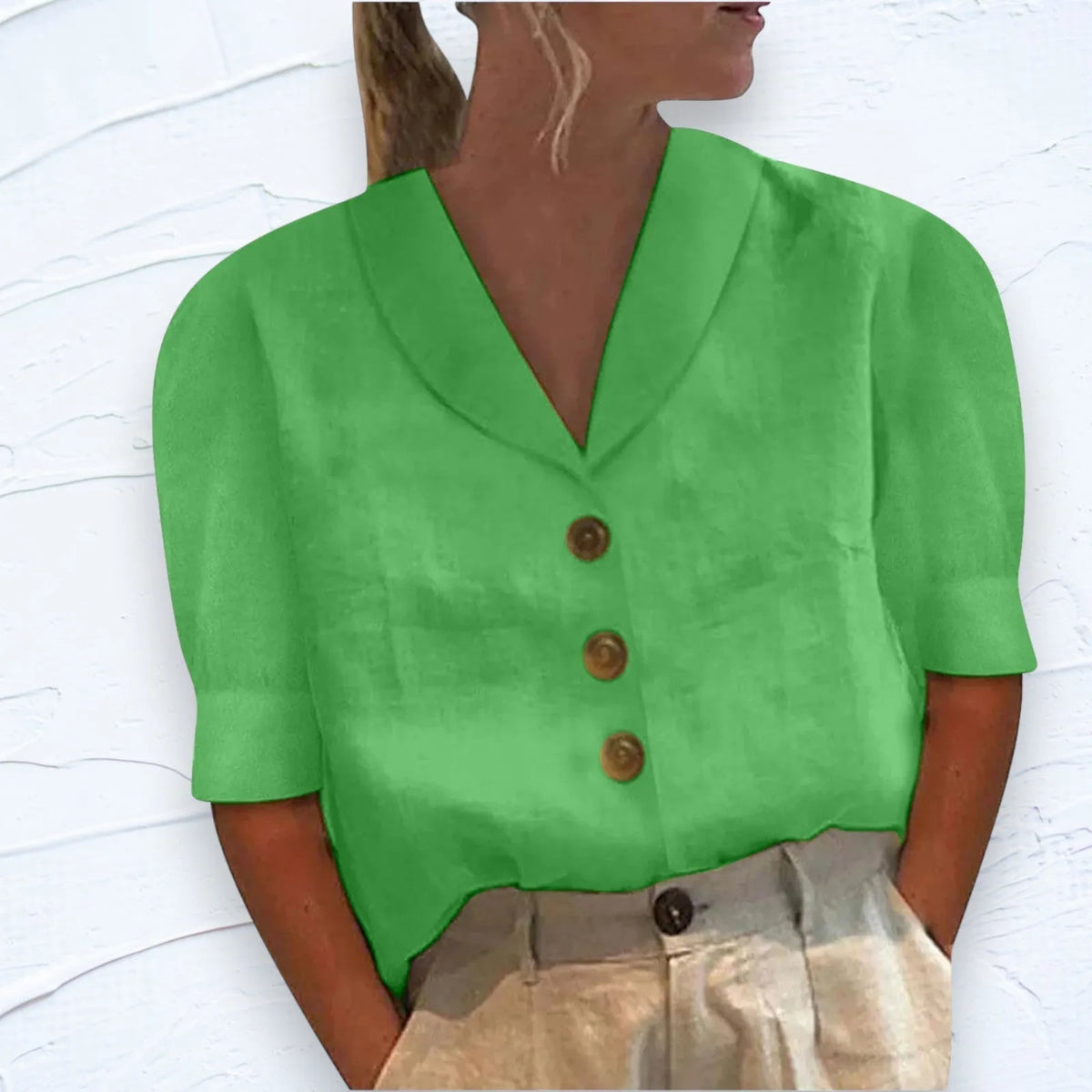 Green shawl V-neck top with cap sleeves and three-button placket, textured woven fabric close up