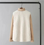Back view of a white sherpa fleece vest on a hanger, worn over a camel ribbed turtleneck jumper
