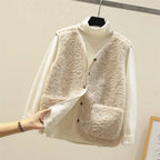 Cream sherpa fleece vest over a white turtleneck jumper, hand pulling back the front edge to show the soft inner lining