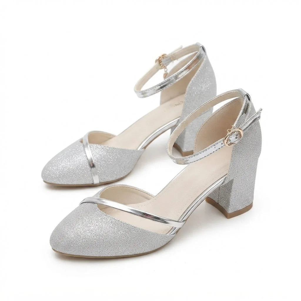 Angled pair view of silver glitter block heel sandals with crisscross ankle straps and metallic silver trim