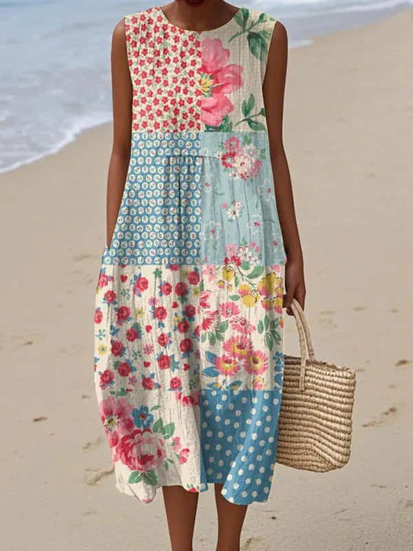 Woman on the beach wearing a sleeveless midi dress with mixed pink floral and polka dot patchwork panels