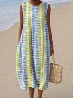 Sleeveless midi dress in white with blue and yellow painted dash print, worn on sandy beach terrain