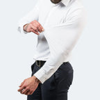Man stretching the sleeve of a white shirt outward to demonstrate the fabric's elasticity and give