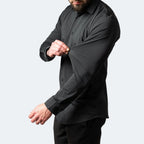 Close-up of a man stretching the sleeve fabric of a black slim-fit shirt to show flexible movement