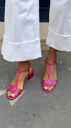 Pink metallic T-bar sandals with strappy front and low block heel, paired with white cropped pants
