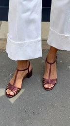 Bordeaux metallic strappy sandals with T-bar strap and block heel, worn with white denim trousers