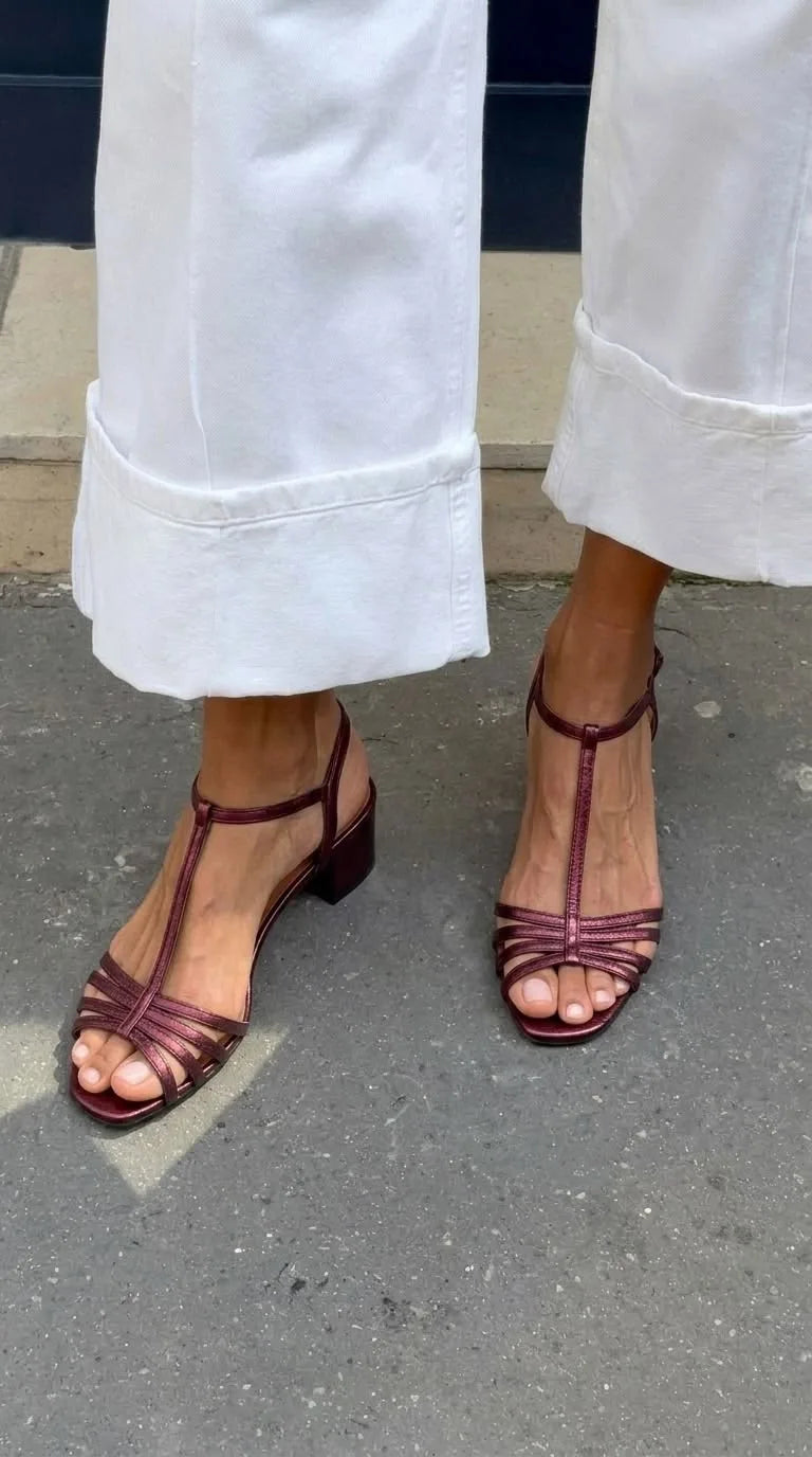 Bordeaux metallic strappy sandals with T-bar strap and block heel, worn with white denim trousers